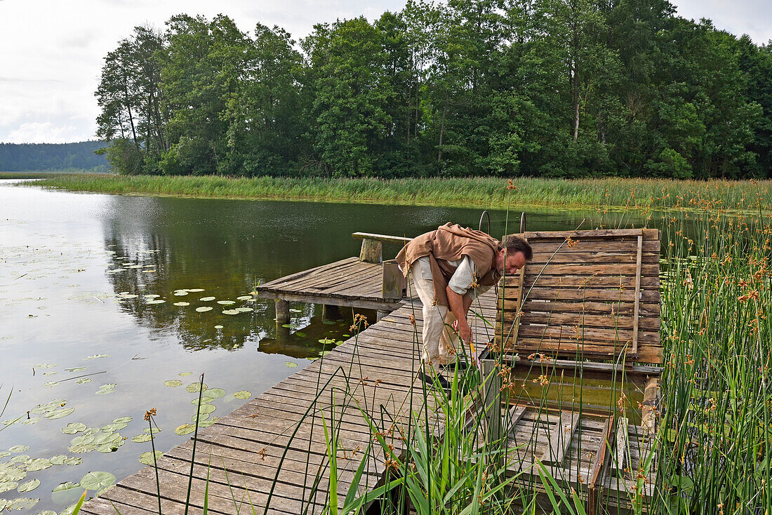 Man taking a fish from a fish tank, Gaideliai rural tourism homestead on the edge of Srovinatis lake, Ginuciai, Aukstaitija National Park, Lithuania, Europe