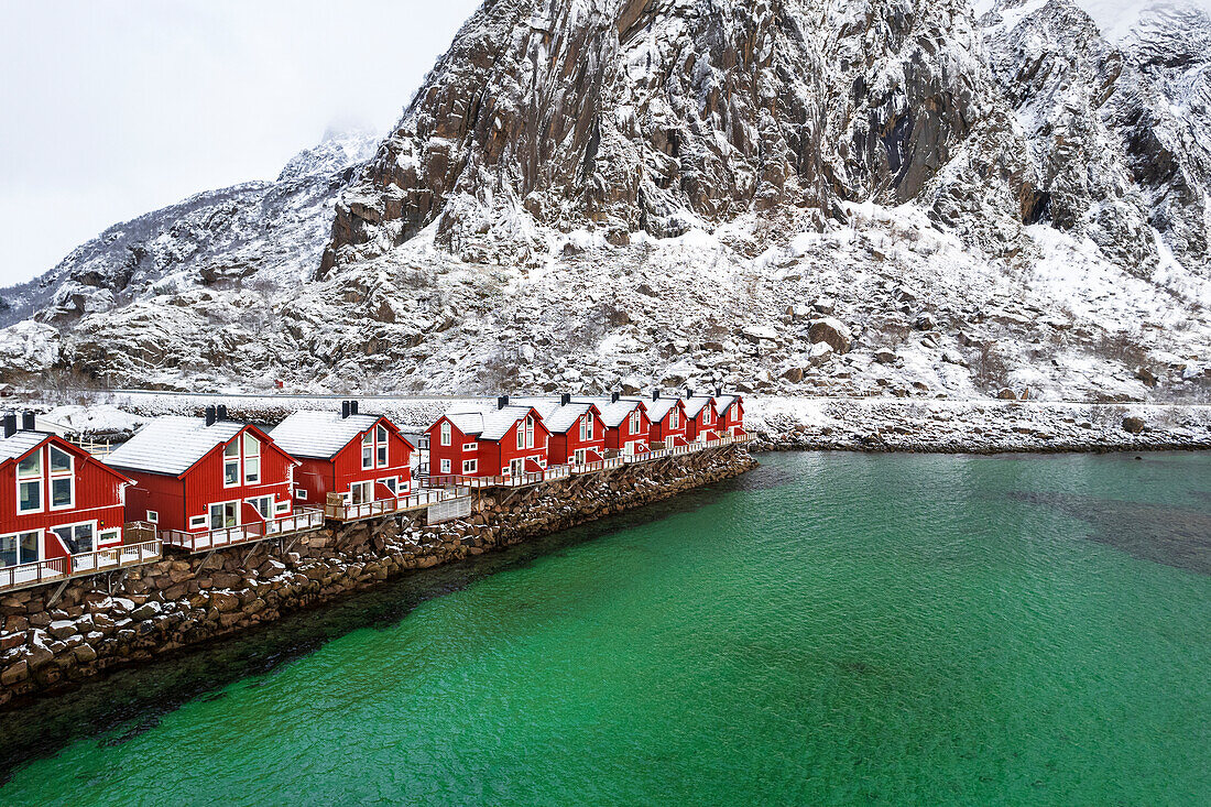 Typische hölzerne Rorbu in Winterlandschaft am smaragdgrünen Wasser des Fjords, Svolvaer, Lofoten Inseln, Norwegen, Skandinavien, Europa