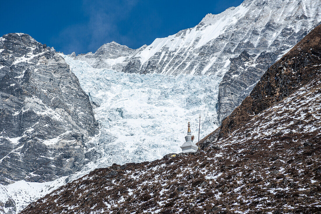 Nahaufnahme einer Stupa (Chorten) an einem Berghang vor Gletschern, Kyanjin Gompa, Langtang-Tal-Trek, Himalaya, Nepal, Asien