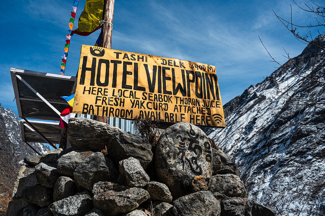 Gelbes Hotelschild auf Felsen vor Berghängen, Langtang-Tal-Trek, Himalaya, Nepal, Asien