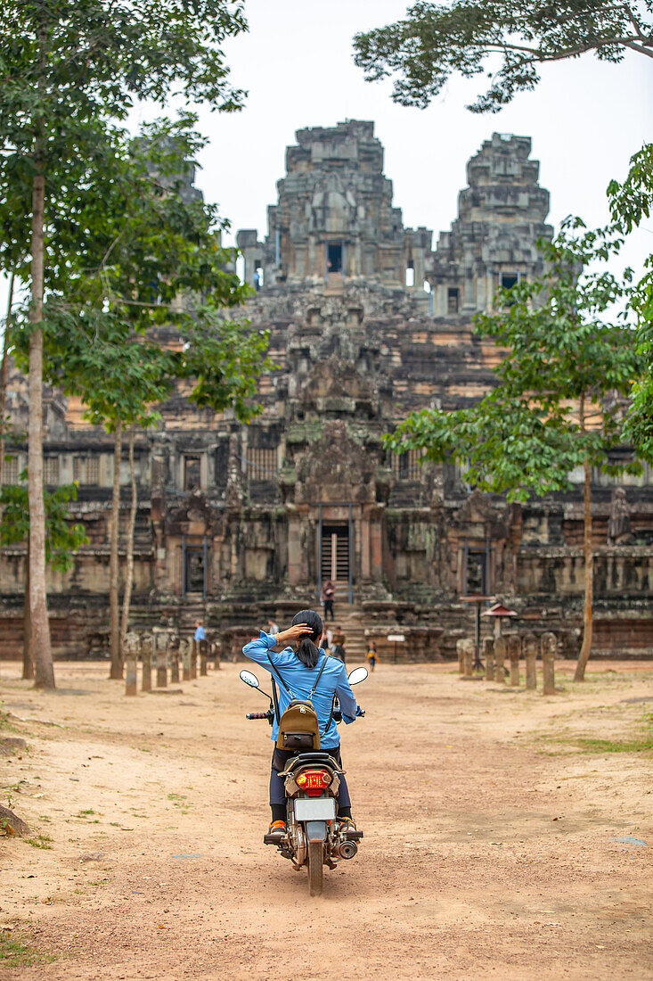 A unidentifed woman riding a scooter towards Banteay Kdei temple in Angkor complex, UNESCO World Heritage Site, Cambodia, Indochina, Southeast Asia, Asia