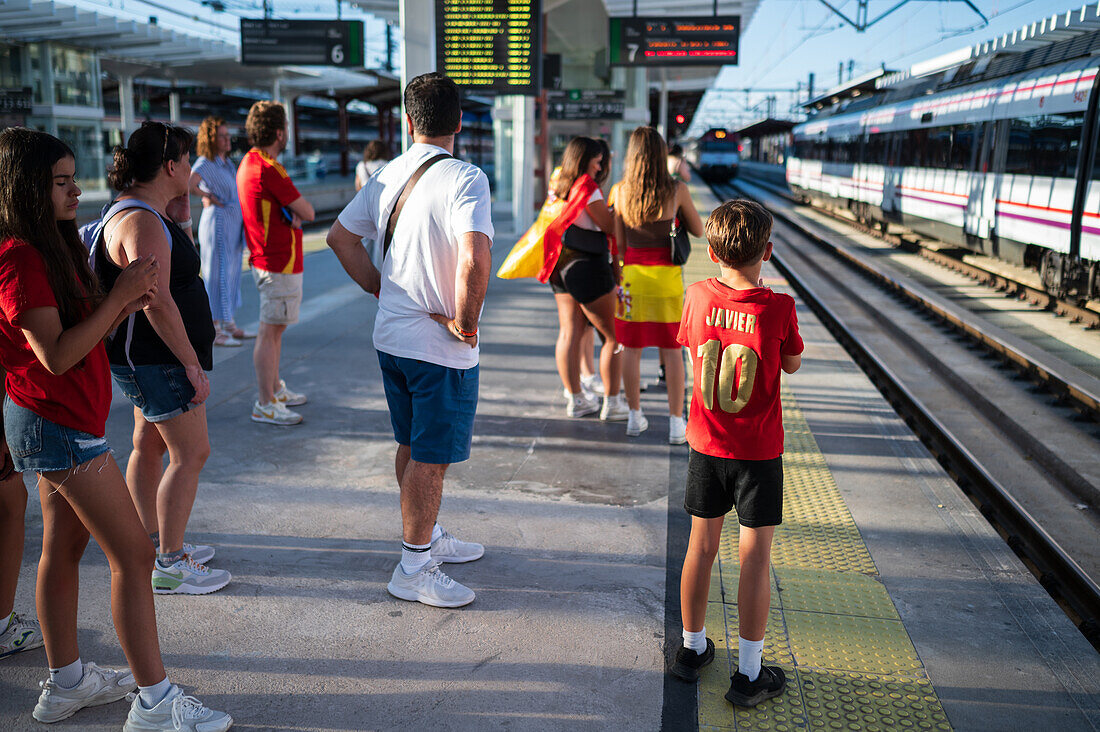 Spanische Fans warten auf den Zug, um an den Feierlichkeiten auf der Straße in Madrid teilzunehmen, nachdem der Europameister Spanien 2024 mit einem königlichen Empfang nach Hause zurückgekehrt ist, Madrid