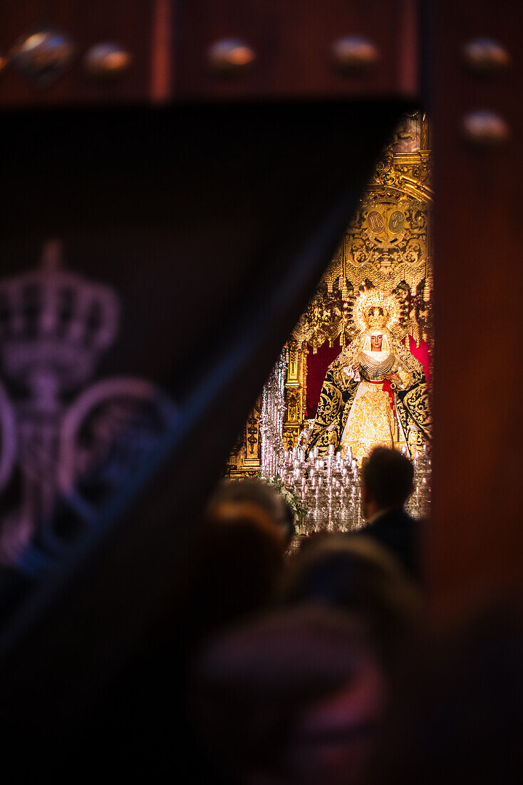 Ein Blick hinter die Vorhänge der Kapelle Capilla de los Marineros in Sevilla, Spanien. Die Gläubigen betreten die Kapelle, um die Esperanza de Triana zu verehren.