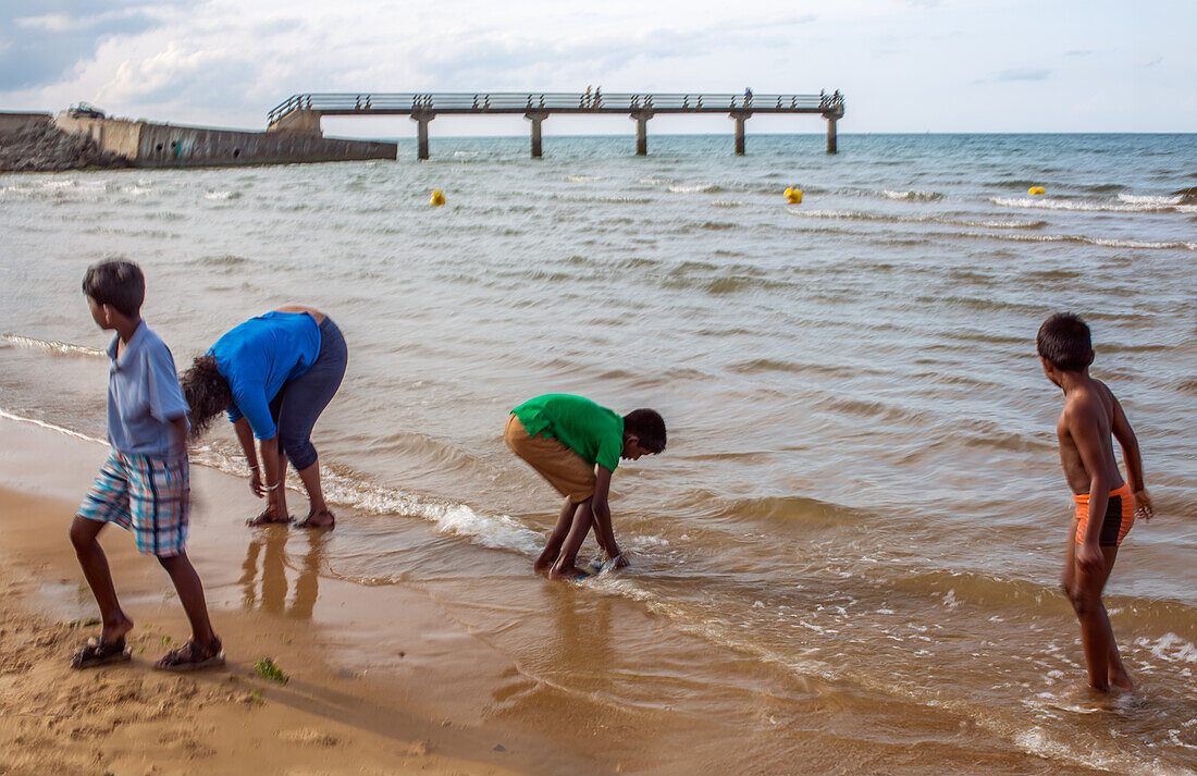 Kinder genießen einen Tag am Omaha Beach, Normandie, Frankreich. Die Szene zeigt Spaß, Erkundung und den historischen Ort am Meer.