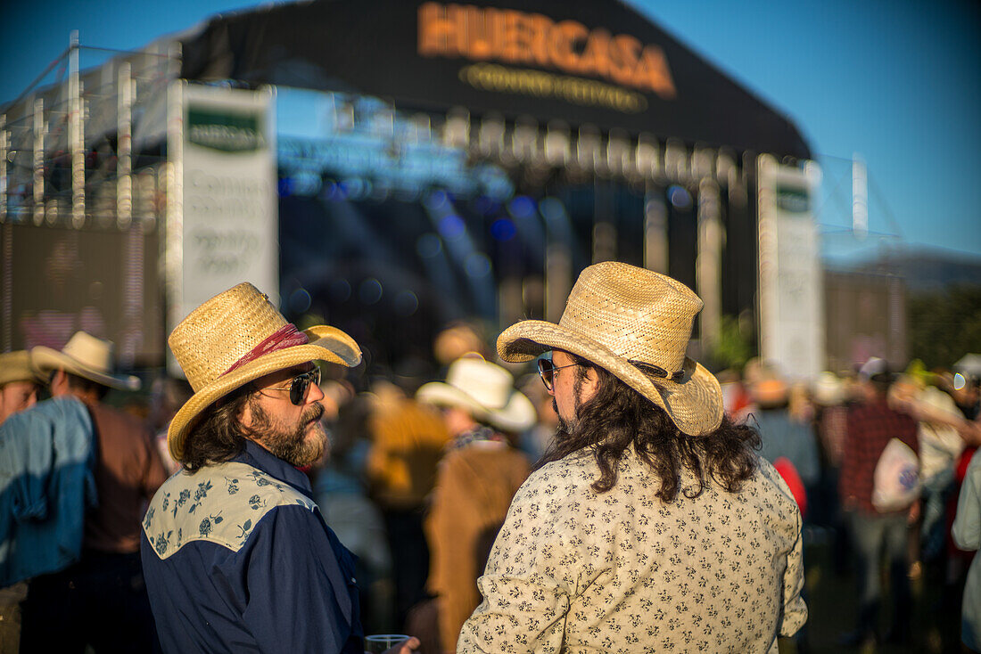 Two people enjoying the Huercasa Country Festival 2017 held in Riaza, Segovia, Spain. The atmosphere is lively and filled with country music enthusiasts.