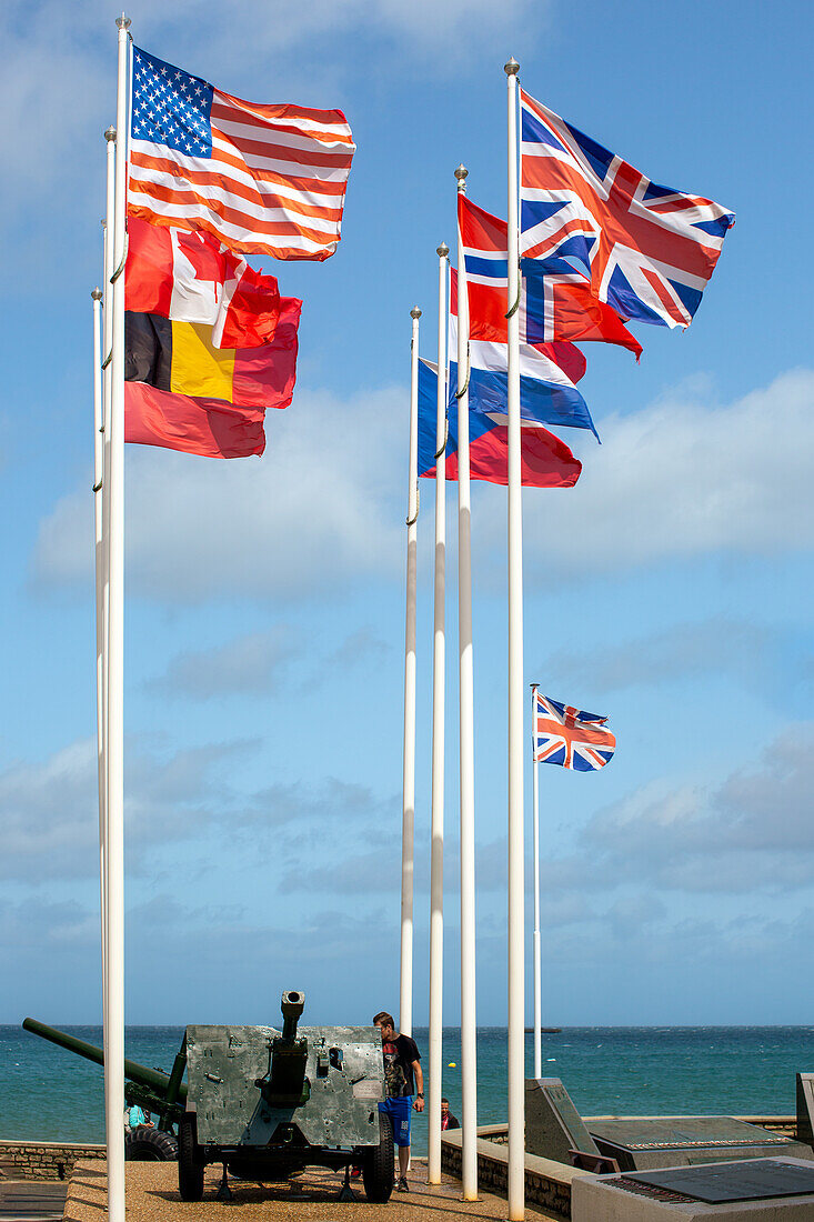 Flaggen der alliierten Nationen wehen am Goldstrand, Arromanches, Normandie, Frankreich. Eine historische Stätte zum Gedenken an die D-Day-Landungen im Zweiten Weltkrieg.