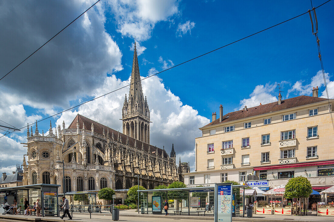 Atemberaubende gotische Kirche Saint-Pierre in Caen, Normandie, Frankreich, mit strahlend blauem Himmel und Wolken. Die Architektur zeichnet sich durch detaillierte Steinarbeiten und einen hohen Kirchturm aus.