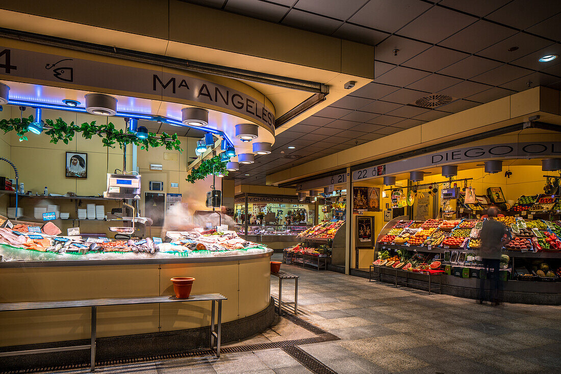 Long exposure photograph showcasing the vibrant and bustling Mercado de la Encarnacion in Sevilla, Spain. The market is filled with fresh produce and a seafood stand.