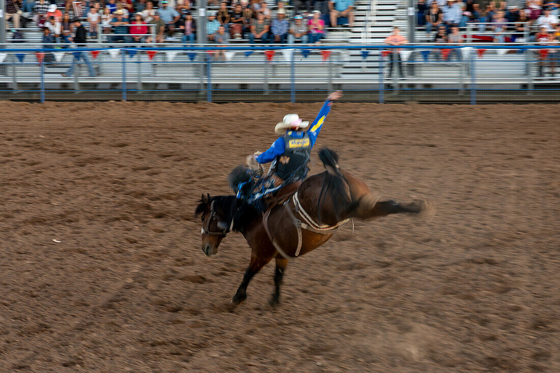 Eine lange Verschlusszeit unterstreicht die Unschärfe eines professionellen Rodeo-Cowboys bei einem Rodeo in Utah.