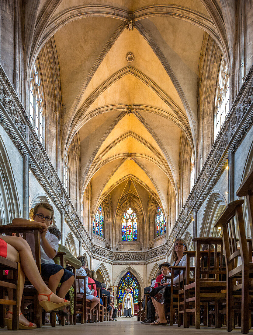 Atemberaubende Ansicht des Innenraums der Eglise Saint Jean in Caen, Normandie, Frankreich, mit sitzenden Menschen und sichtbaren Glasmalereien.