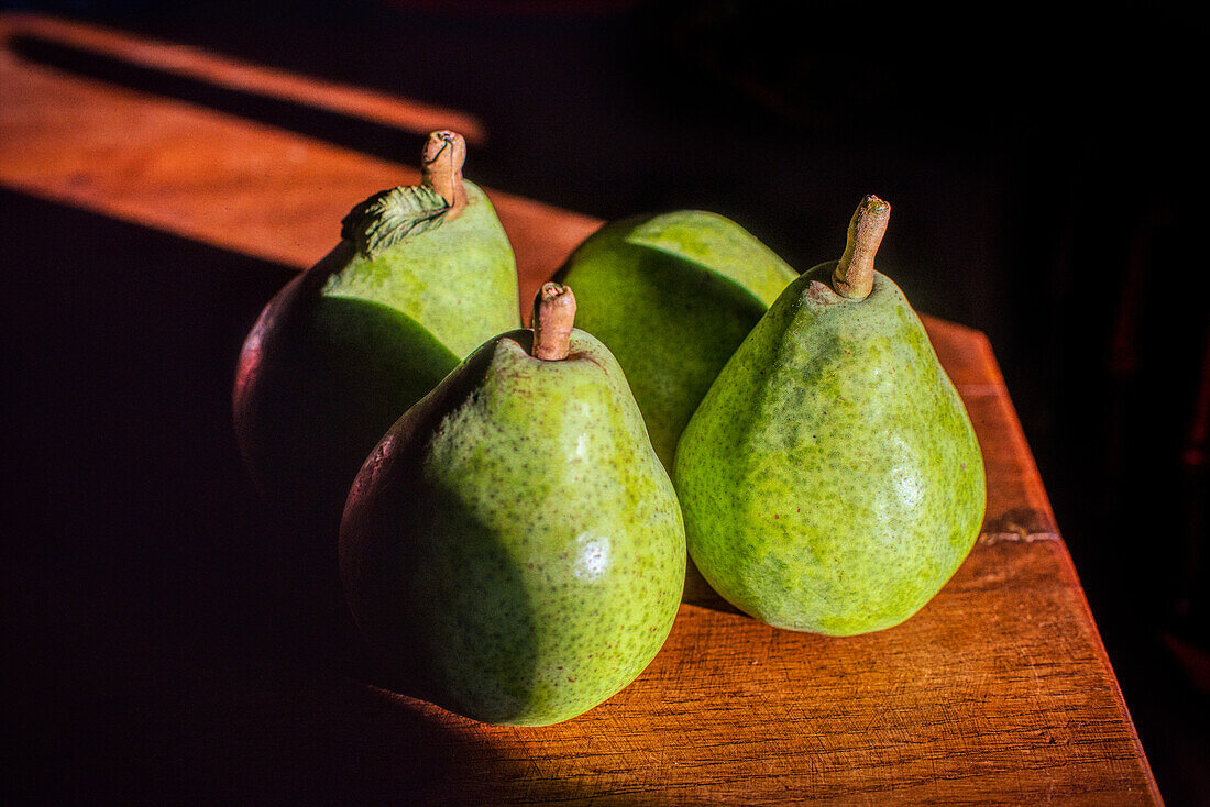 Close up of fresh green pears on a wooden table in Fuenteheridos, Huelva, Andalusia, Spain. Rustic and natural setting.