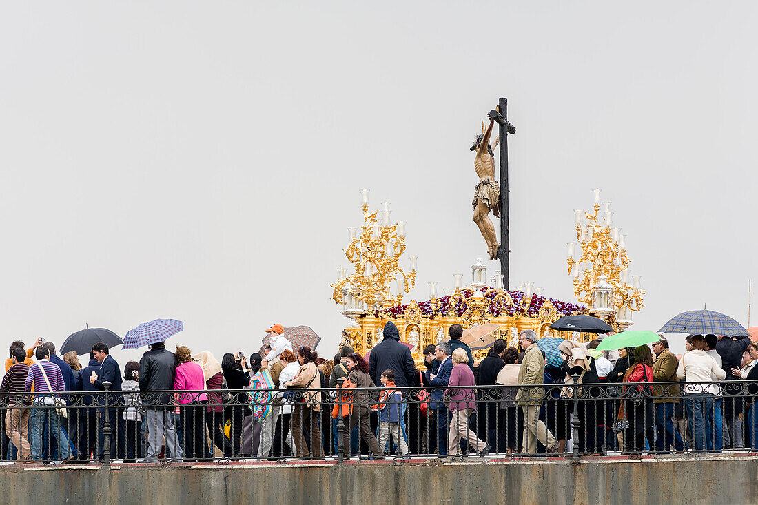 Der Cristo de la Expiracion aus dem 17. Jahrhundert überquert die Triana-Brücke in Sevilla während der Semana Santa im Regen.