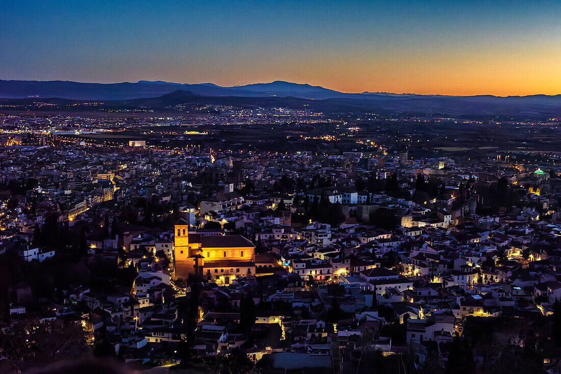 Ein schöner Blick auf Granada, Andalusien, Spanien in der Abenddämmerung, aufgenommen vom Aussichtspunkt San Miguel Alto. Die Lichter der Stadt funkeln in der Dämmerung.