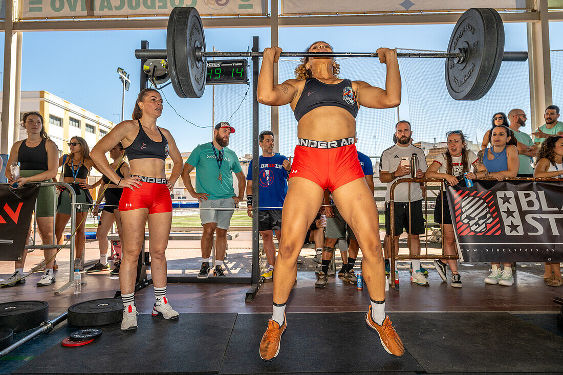 Teilnehmer heben schwere Gewichte während eines Crossfit-Wettbewerbs in Sevilla, Spanien. Die Veranstaltung demonstriert Stärke, Entschlossenheit und Sportlichkeit.