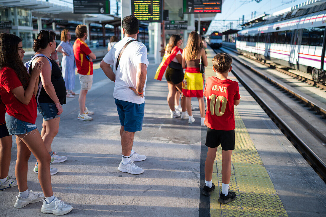 Spanische Fans warten auf den Zug, um an den Feierlichkeiten auf der Straße in Madrid teilzunehmen, nachdem der Europameister Spanien 2024 mit einem königlichen Empfang nach Hause zurückgekehrt ist, Madrid