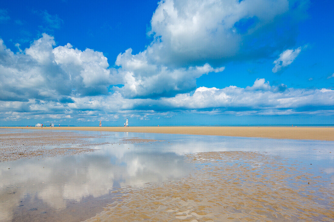 A beautiful landscape of Utah Beach in Normandy, France, featuring a vast sandy shore and clear blue skies.