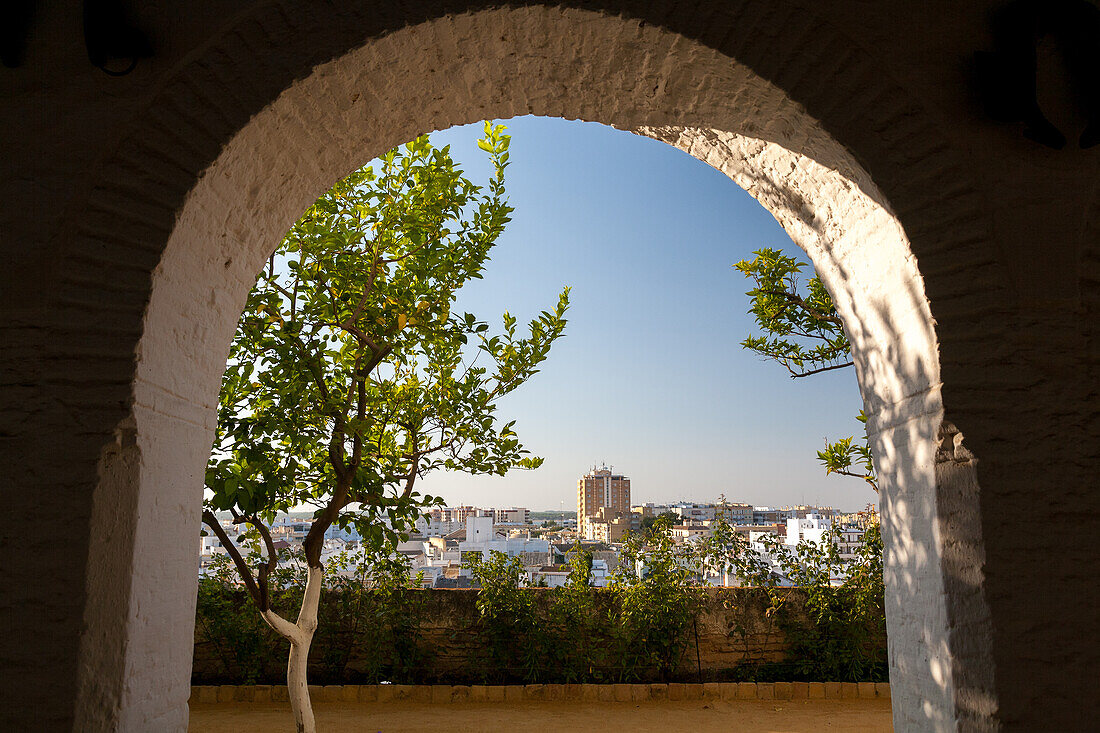 A picturesque view of Sanlucar de Barrameda, in the province of Cadiz, Andalusia, Spain, seen through a charming stone archway.