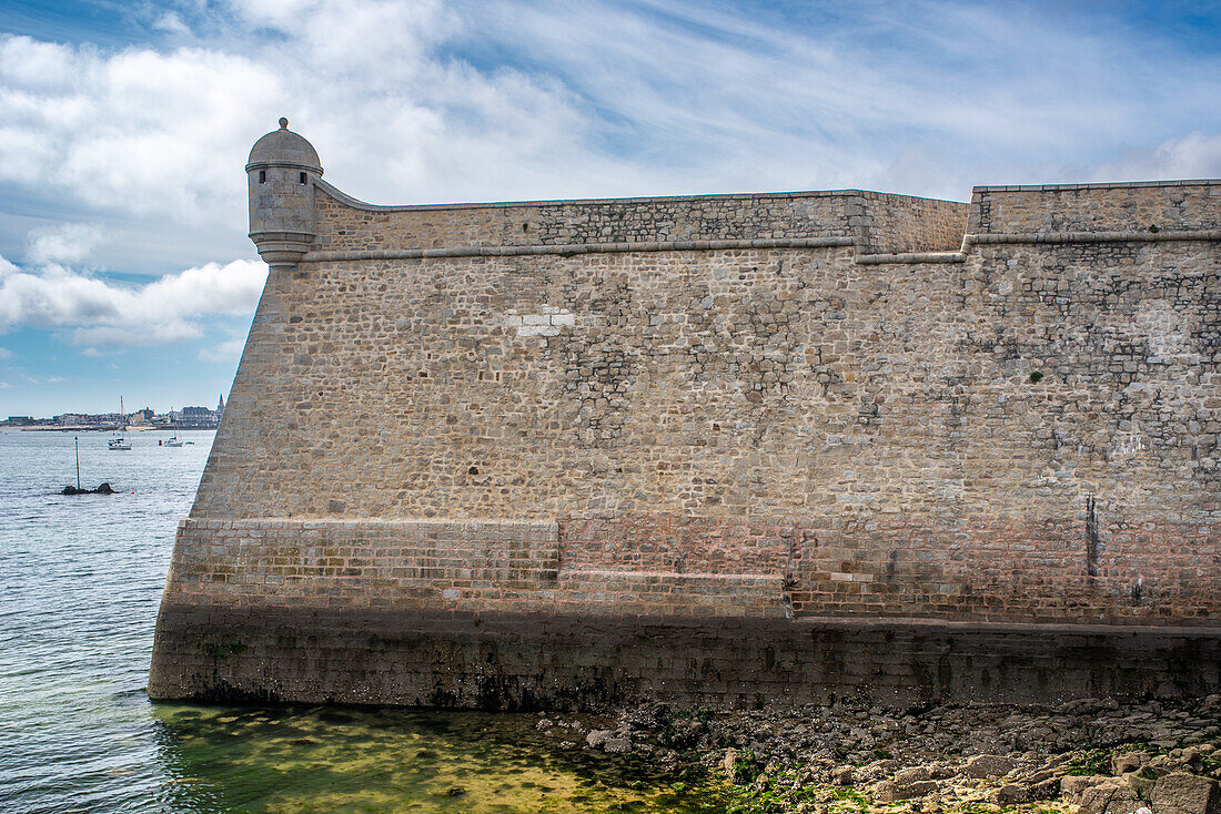 Historic stone wall of Port Louis Citadelle in Lorient, Brittany, France, offering a scenic view over the sea.