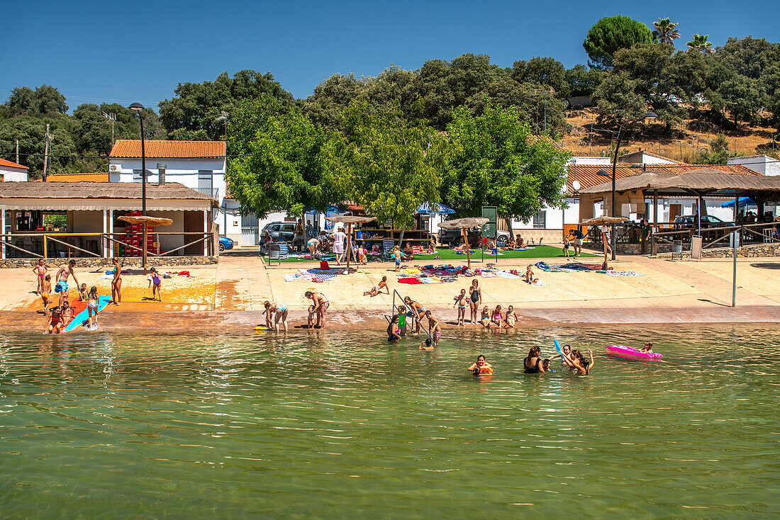 Familien und Kinder genießen einen sonnigen Tag am Flussstrand in San Nicolas del Puerto, Sevilla, Spanien.