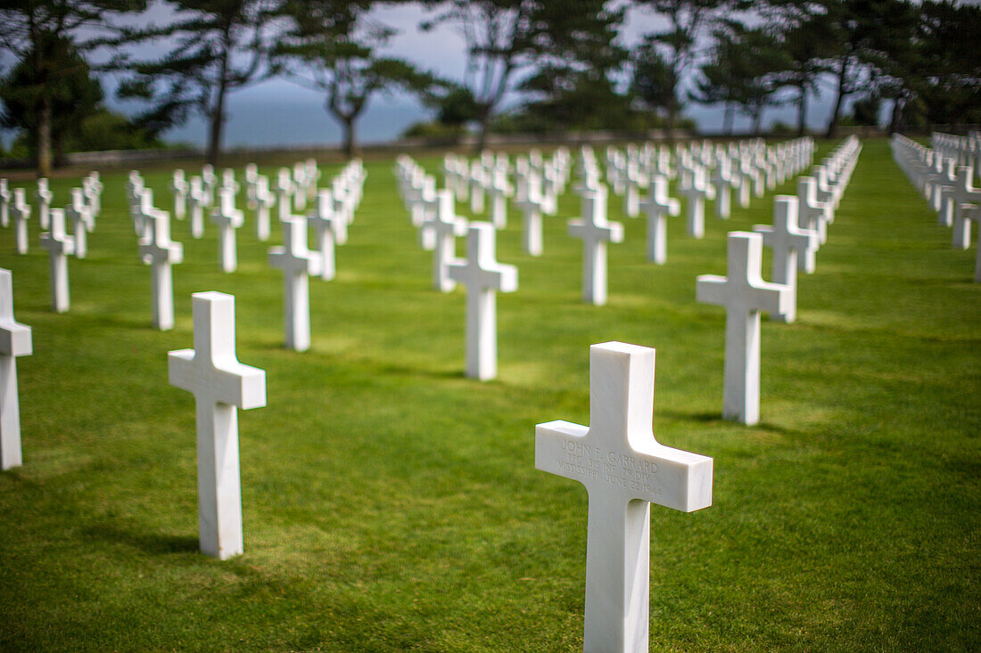 Rows of white crosses at the American military cemetery in Normandy, France, commemorating fallen soldiers from World War II.