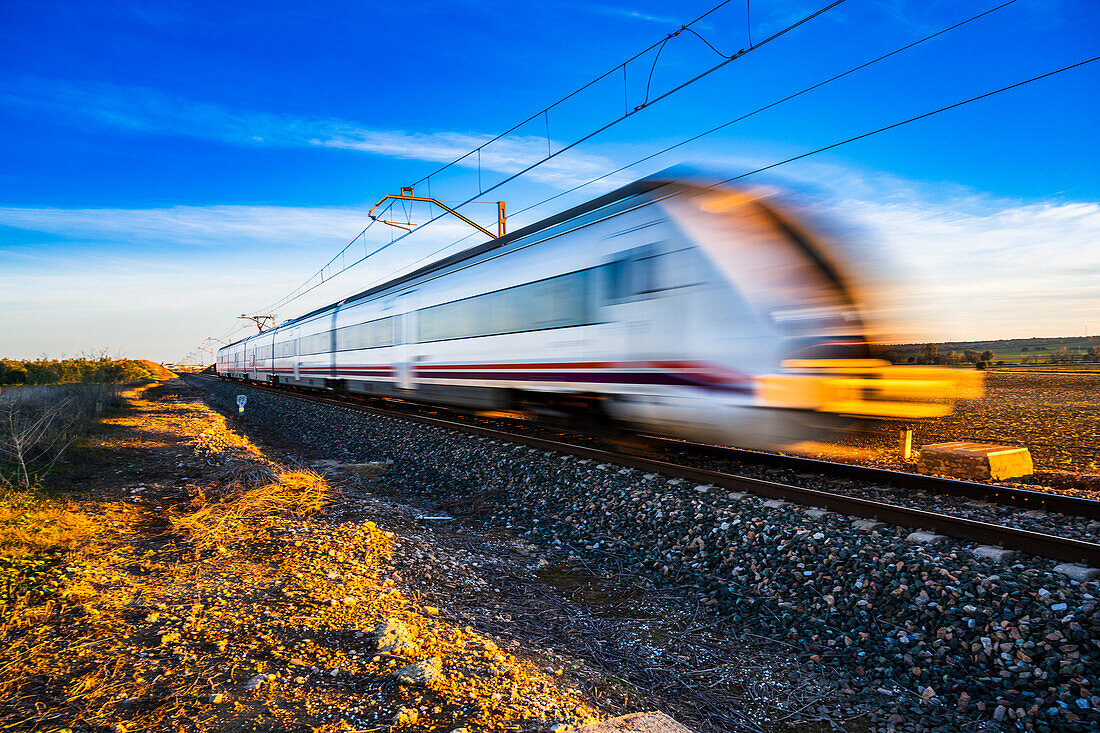 A high-speed train blurs by on the tracks through the countryside near Carrion de los Cespedes in the province of Sevilla, Andalusia, Spain.