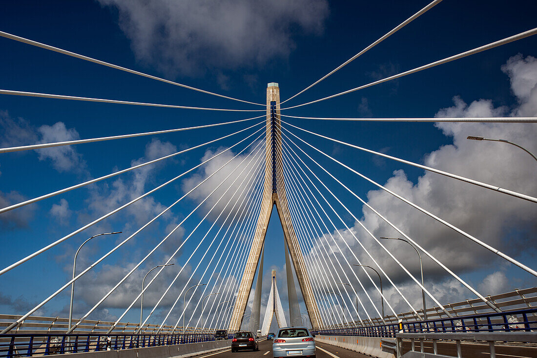 Photo of the Constitution of 1812 Bridge, also known as La Pepa Bridge, located in Cadiz, Andalusia, Spain with cars driving under a blue sky.