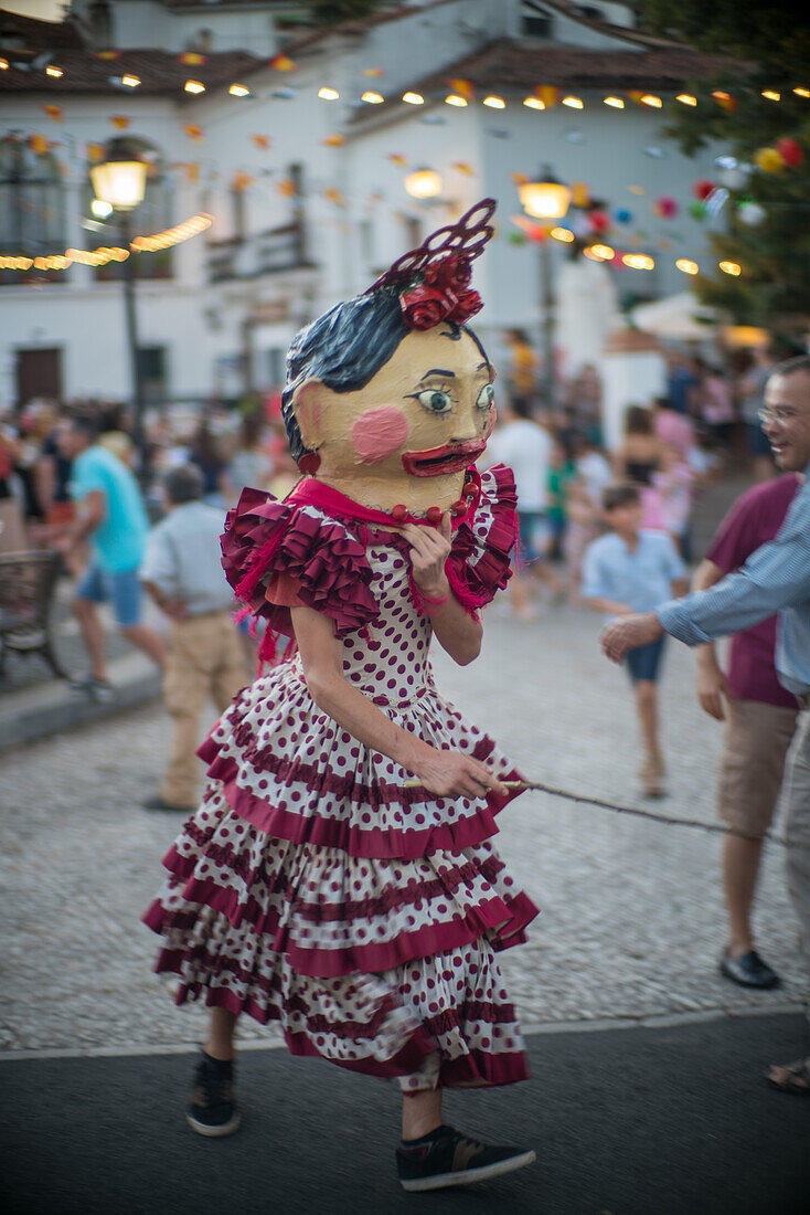 Festivities in Fuenteheridos, Andalucia, featuring traditional Gigantes y Cabezudos parade with vibrant costumes. Crowds enjoying cultural events and celebrations.