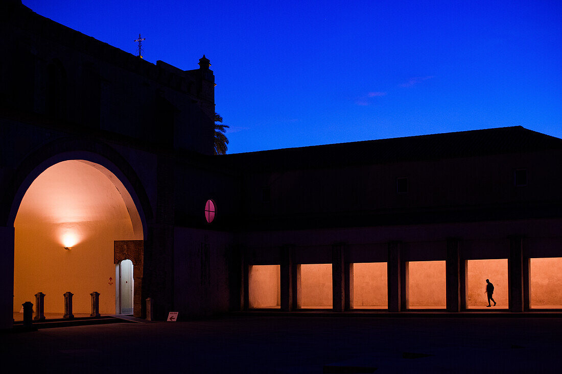 A stunning night view of the illuminated Patio at the Centro de Arte Contemporáneo in Monasterio de la Cartuja, Sevilla, España. An example of beautiful architecture and atmospheric lighting.