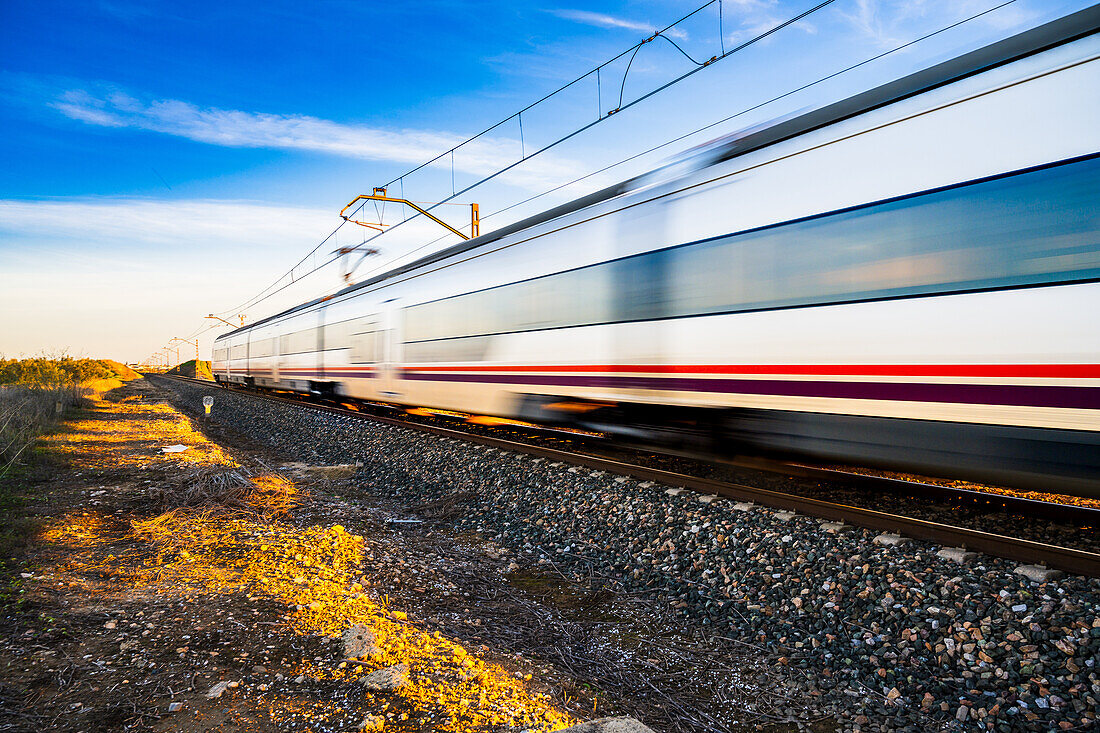 A high-speed train blurs by on the tracks through the countryside near Carrion de los Cespedes in the province of Sevilla, Andalusia, Spain.