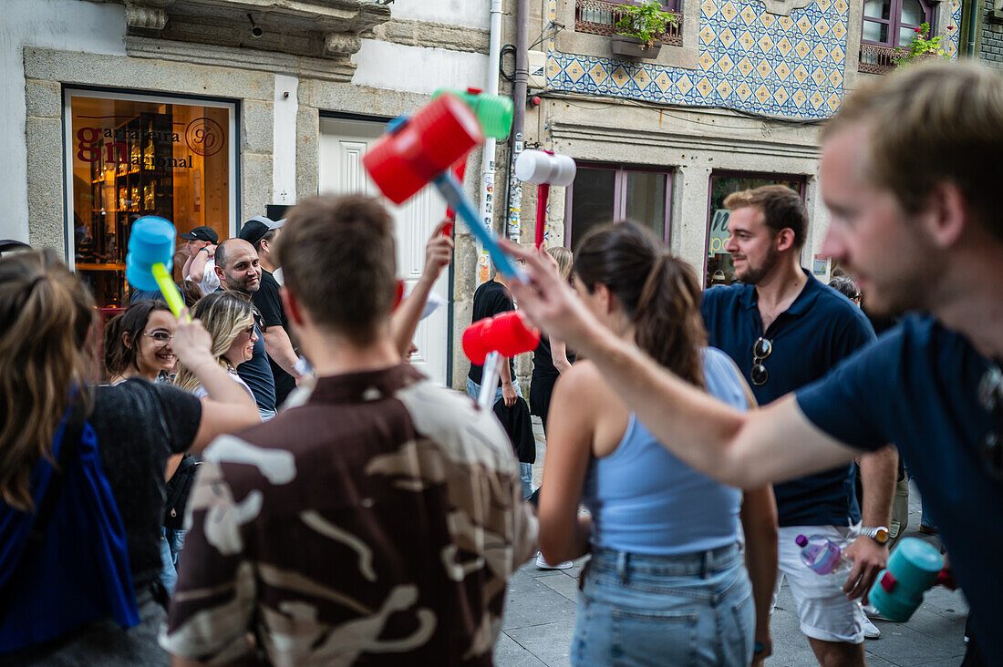 Begrüßung von Menschen mit welkem Lauch und Plastikhämmern während des Johannisfestes (Festa de Sao Joao do Porto ) im Hochsommer, in der Nacht zum 23. Juni (Johannisnacht), in der Stadt Porto, Portugal