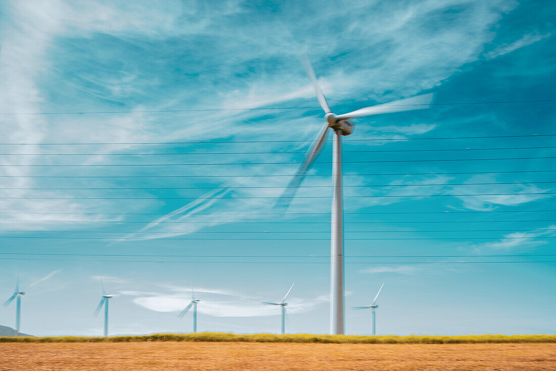 Windturbinen zur Erzeugung erneuerbarer Energie vor einem strahlend blauen Himmel in Tarifa, Spanien. Das Bild fasst das Konzept der nachhaltigen Energie zusammen.