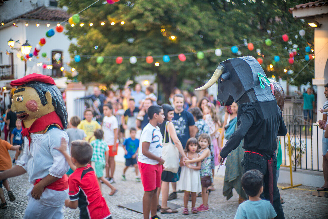 Menschen genießen das traditionelle Gigantes y Cabezudos-Fest in Fuenteheridos, Huelva, Andalusien, Spanien, mit bunten Dekorationen und festlicher Atmosphäre.