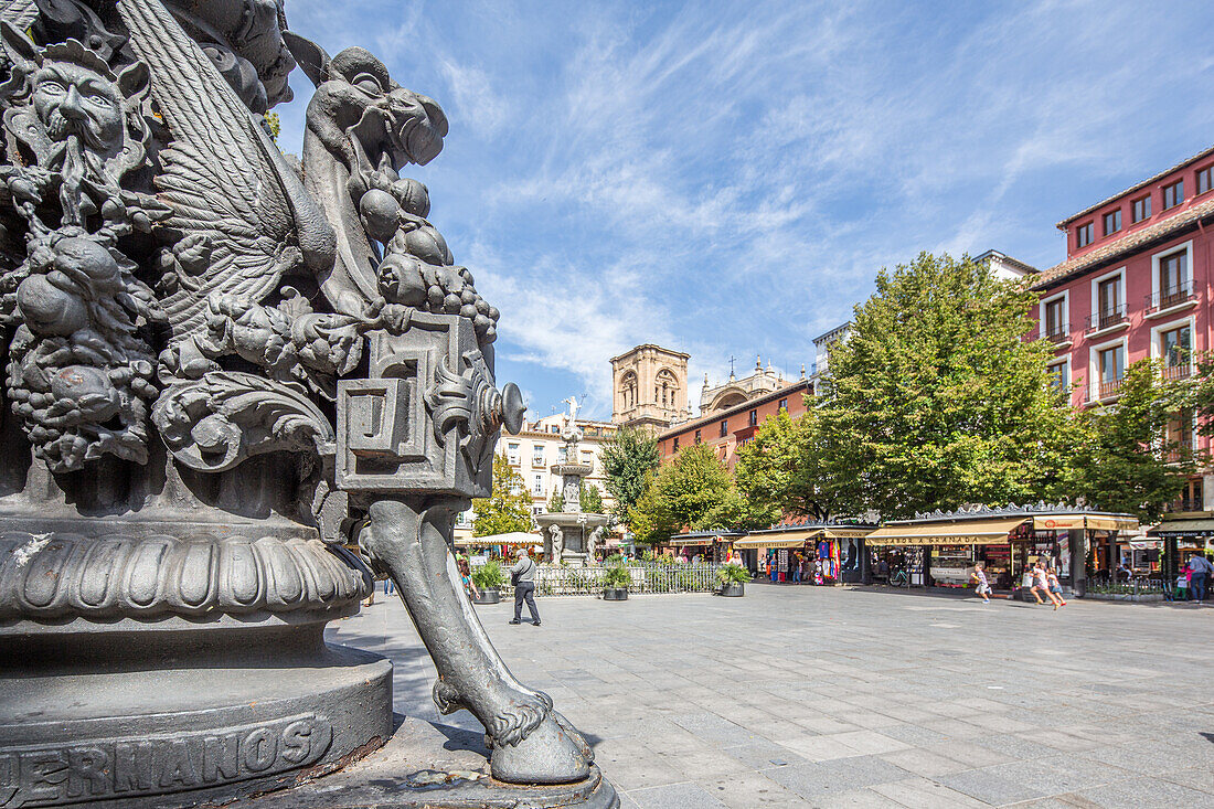 Detaillierte mythologische Figuren auf einem schmiedeeisernen Laternenpfahl auf der Plaza de Bib Rambla mit der Kathedrale im Hintergrund in Granada, Spanien.