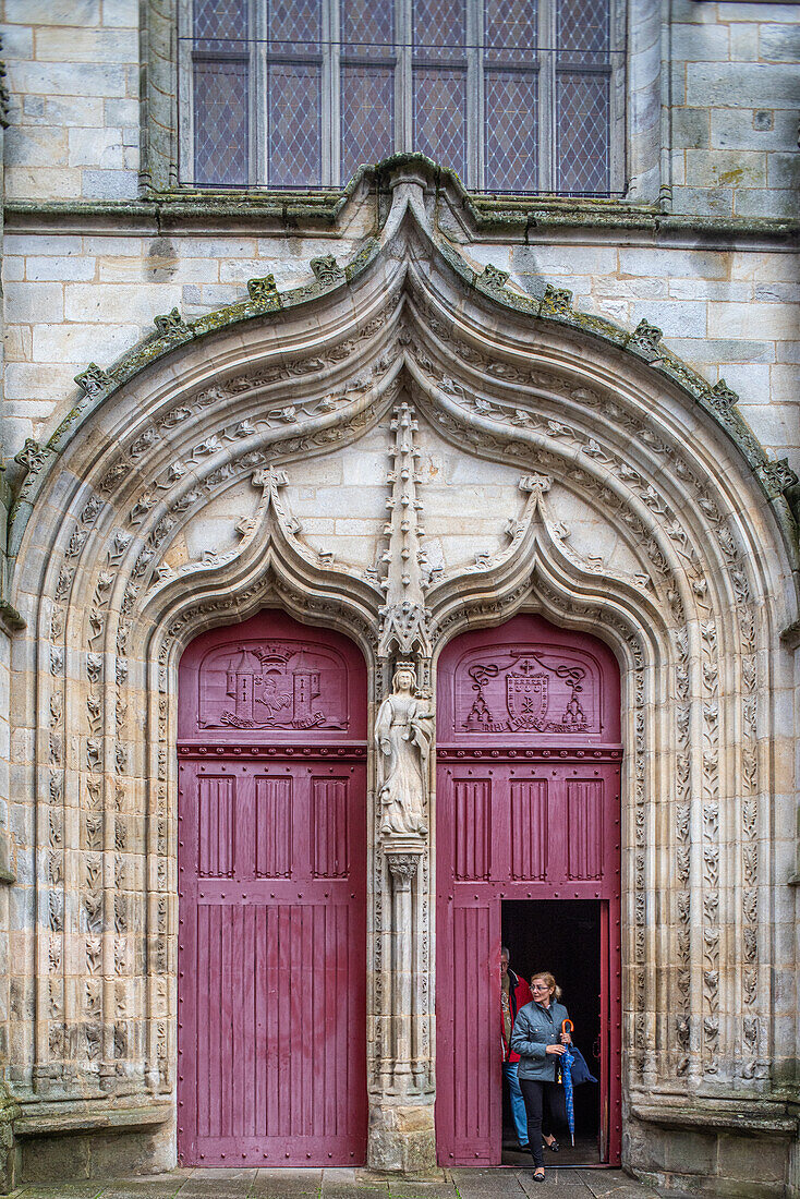 Eine Nahaufnahme des komplizierten gotischen Portals der Basilika Notre Dame du Roncier in Josselin, Bretagne, Frankreich, die die detaillierte Architektur hervorhebt.