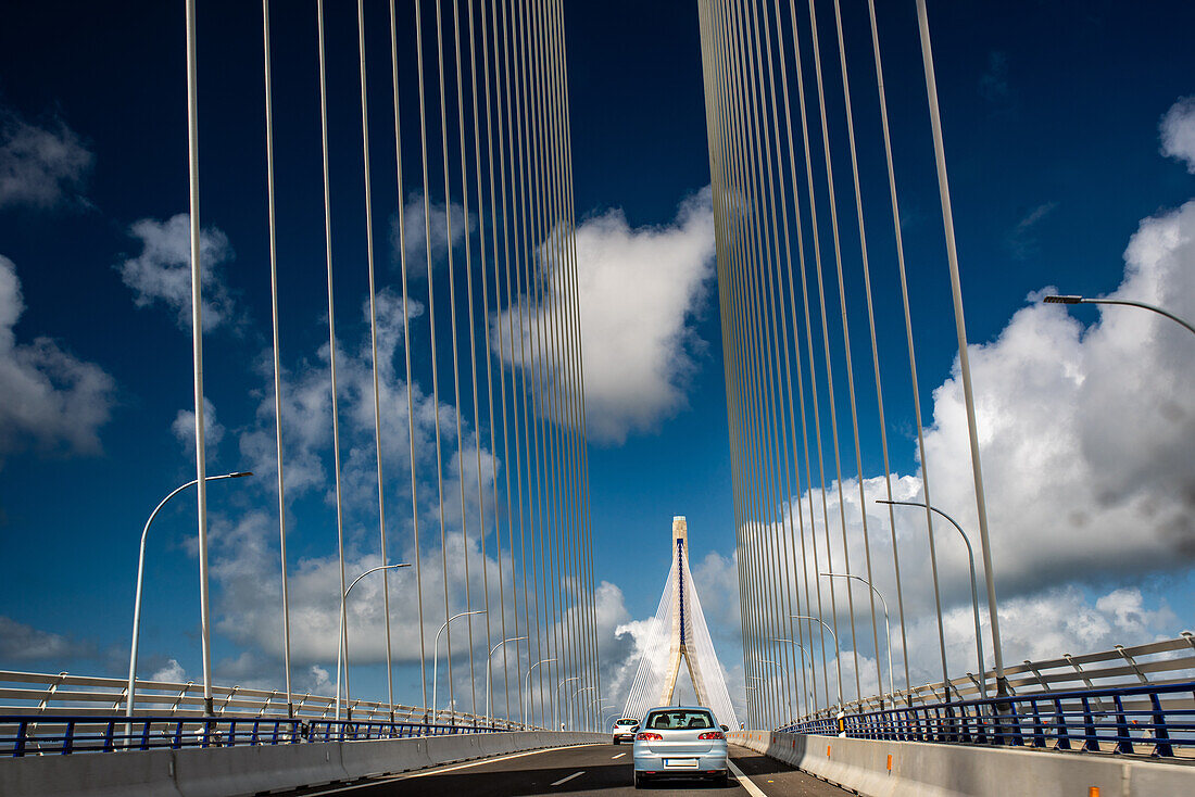 Foto der Brücke über die Verfassung von 1812, auch bekannt als La Pepa-Brücke, in Cádiz, Andalusien, Spanien, mit fahrenden Autos unter blauem Himmel.