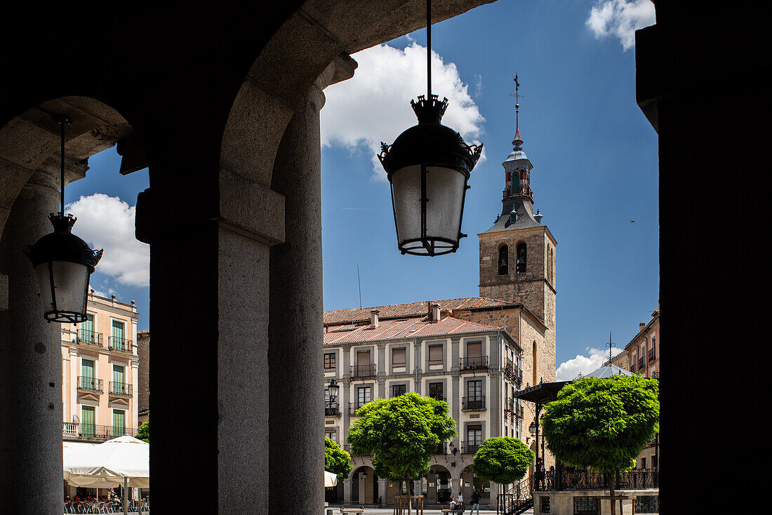 Blick auf den Turm der Kirche San Miguel von den Säulengängen der Plaza Mayor in Segovia, Kastilien-León, Spanien. Schöne architektonische Szenerie.