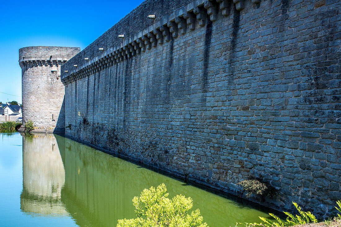 Picturesque view of the historic Guerande wall and its surrounding moat on a sunny day in Brittany, France.