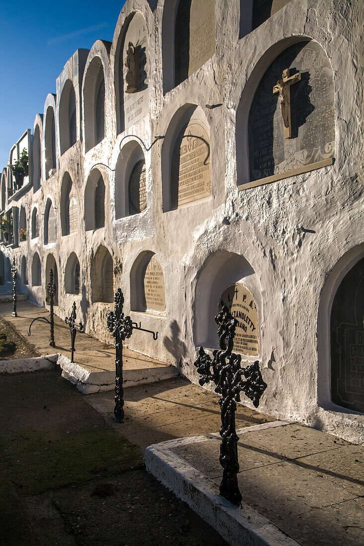 Historical Catholic cemetery wall in Aznalcazar, located in the Seville province of Andalusia, Spain. The peaceful location showcases a row of tombstones with intricate crosses.