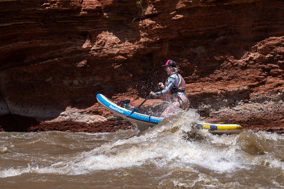 Eine junge Frau paddelt im Wildwasser des White's Rapid auf dem Colorado River bei Moab, Utah.