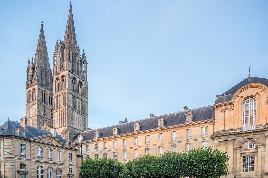 Die historische Abtei der Männer und das Rathaus (rechts) in Caen mit ihren gotischen Türmen vor einem heiteren Himmel.