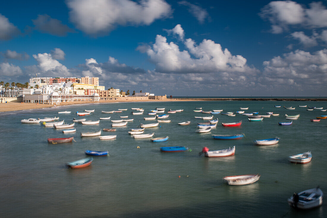 Langzeitbelichtung von Booten vor Anker am Playa de la Caleta in Cadiz, Andalusien, Spanien. Ein sonniger Tag mit vereinzelten Wolken.