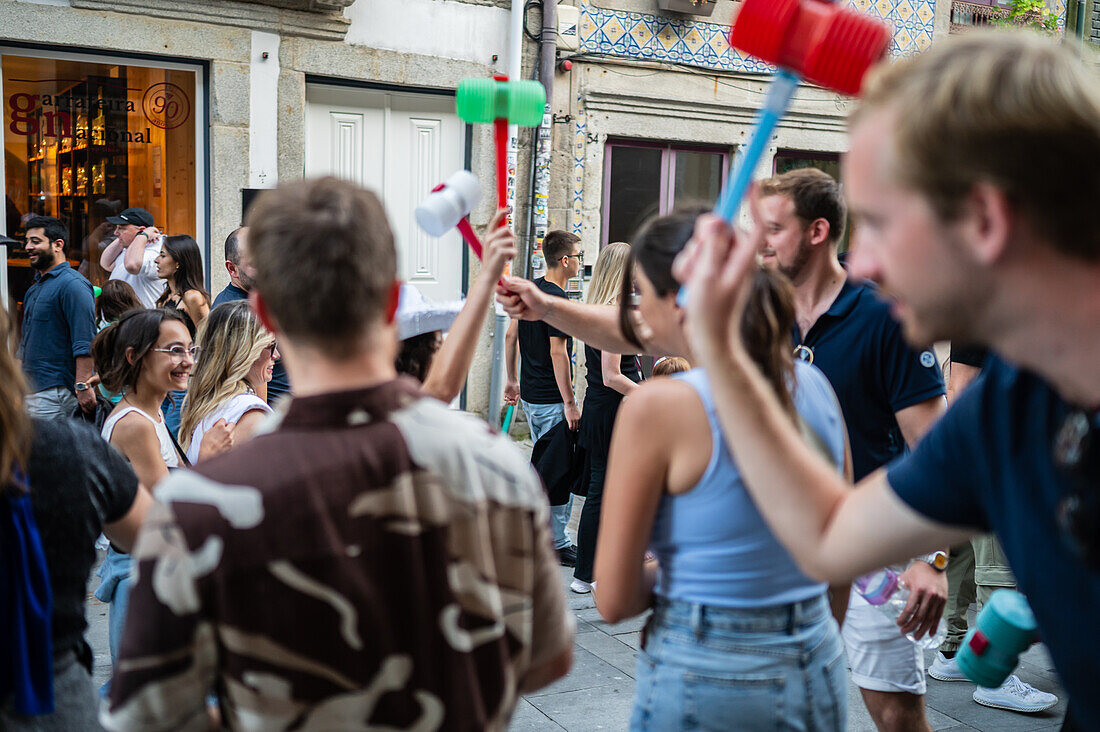 Begrüßung von Menschen mit welkem Lauch und Plastikhämmern während des Johannisfestes von Porto (Festa de Sao Joao do Porto ) in der Nacht zum 23. Juni (Johannisnacht) in der Stadt Porto, Portugal