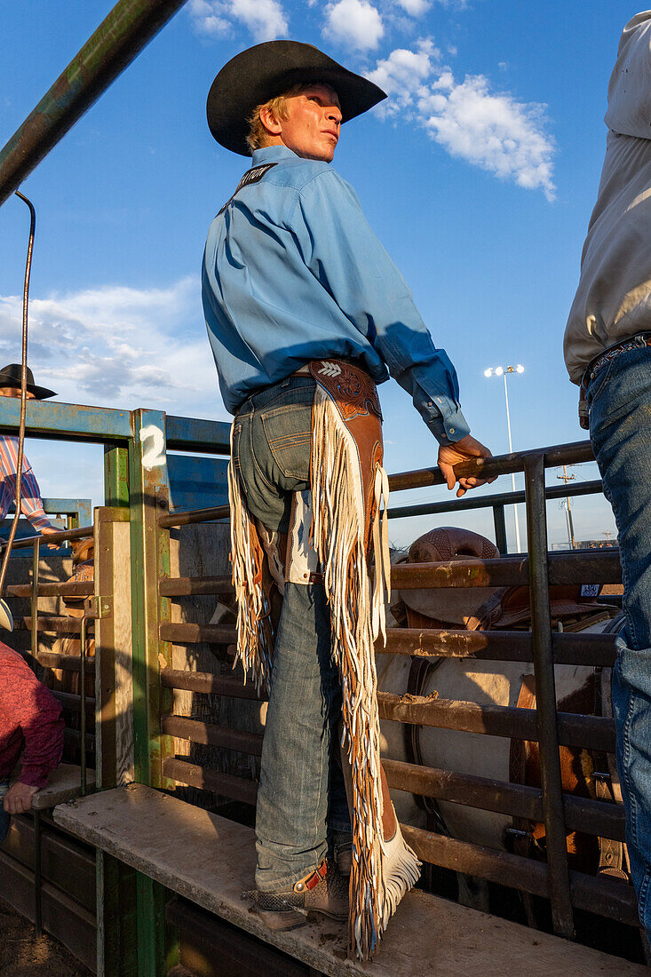 Cowboy Josh Davison in seinen fransenbesetzten Lederchaps steht bei einem Rodeo im ländlichen Utah an den Bucking Chutes.