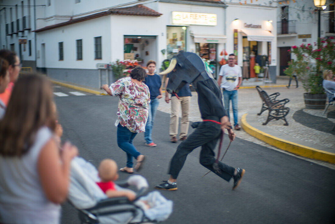 A vibrant street scene capturing the traditional Gigantes y Cabezudos celebration during the festivities in Fuenteheridos, Huelva province, Andalucia, Spain.