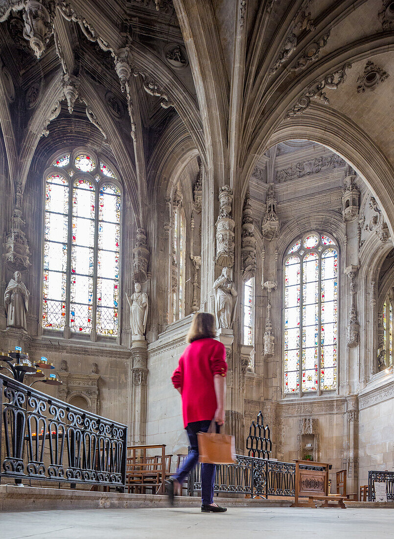 A person exploring the beautiful interior of Eglise Saint Pierre in Caen, Normandy, France, showcasing stunning Gothic architecture and stained glass windows.