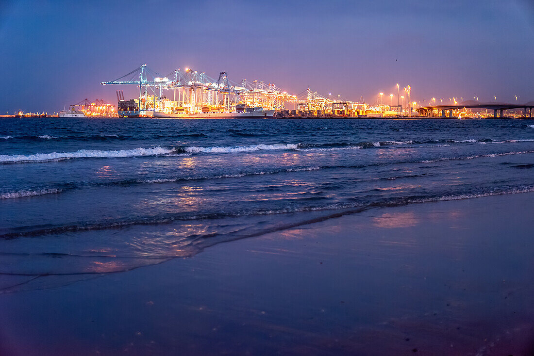 Der Strand von El Rinconcillo bei Nacht mit einem schönen Blick auf den beleuchteten Hafen von Algeciras im Hintergrund, Spanien.