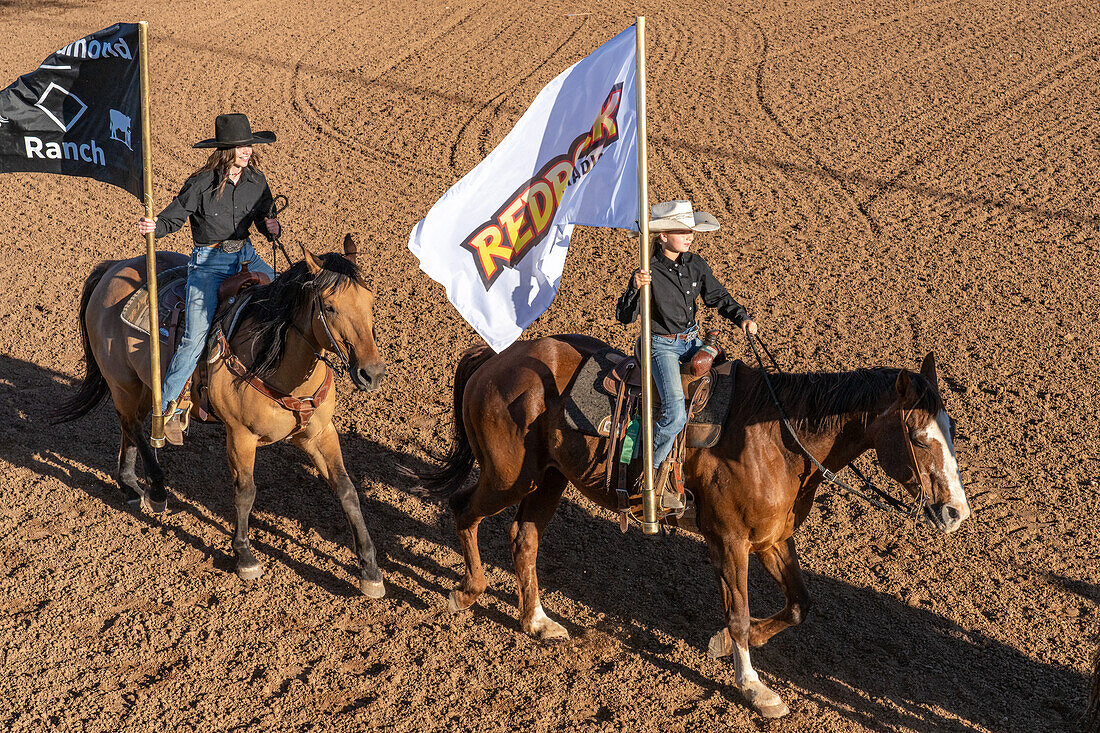 Junge Cowgirls tragen bei einem Rodeo in einer ländlichen Kleinstadt in Utah die Flaggen der Sponsoren beim Grand Entry.