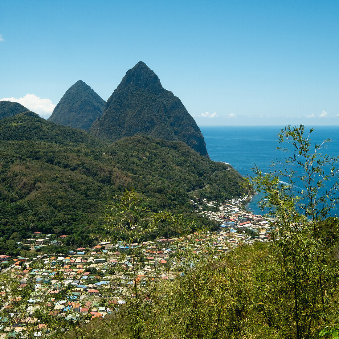 Stadt in Hügellandschaft mit Meer im Hintergrund