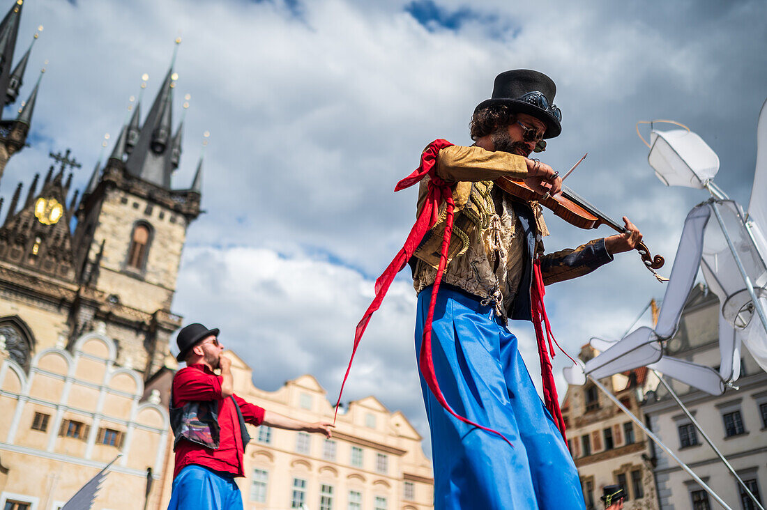 Künstlerin spielt Geige, während sie auf Stelzen bei der Puppenparade vom Marienplatz zum Altstädter Ring läuft, während des Prager Straßentheaterfestivals Behind the Door, Prag, Tschechische Republik