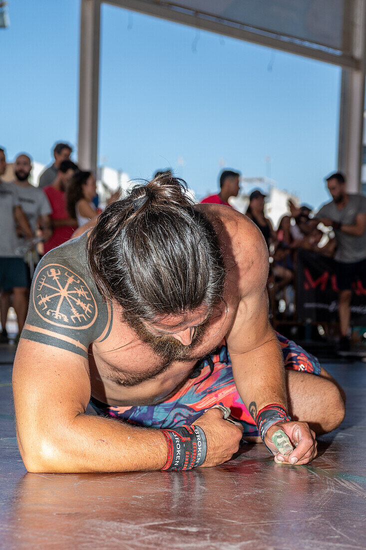 A fatigued athlete takes a moment to recover after a demanding CrossFit competition in Sevilla, España, showcasing strength and endurance.